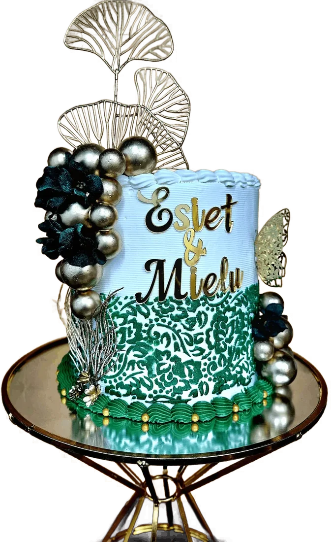 Green and white patterned celebration cake with feather topper