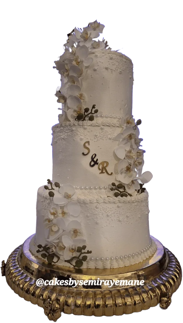 Three-level white wedding cake with white orchids and initials on a gold stand