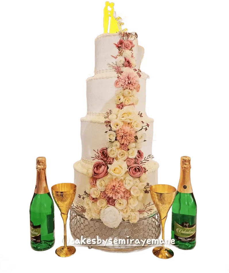Ivory wedding cake with peach flowers between two champagne bottles